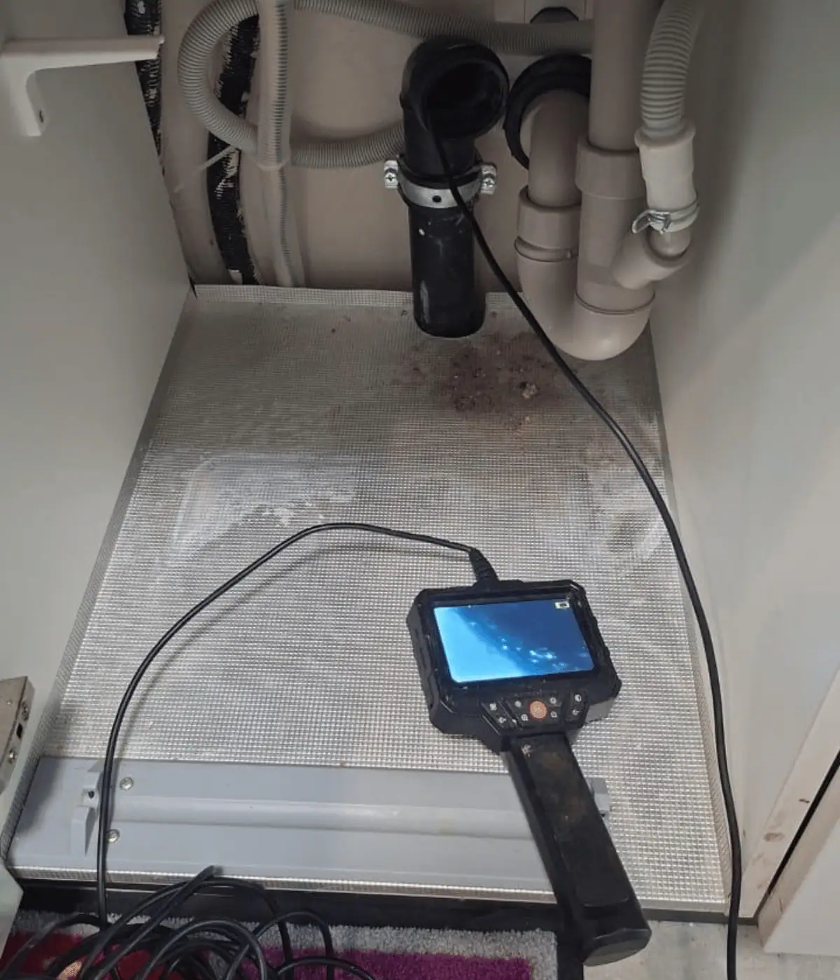 Caméra d'inspection engagée sous un meuble d'évier pour localiser une fuite sur l'évacuation.